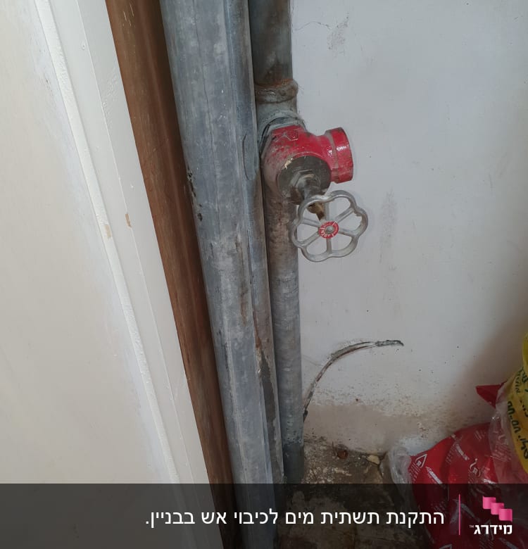 צינורות מתכת עם ברז אדום על קיר